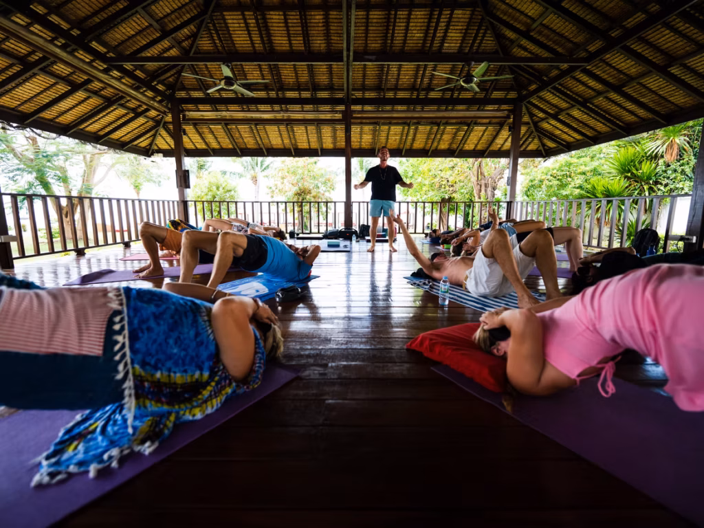 A group of people practicing breathwork together in a serene open-air sala at Health Republic, Koh Samui, guided by an instructor, surrounded by peaceful natural surroundings.